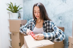 Woman sealing boxes with tape for relocation in a cozy indoor setting. — Experienced Winnipeg Moving Company Serving Homes an