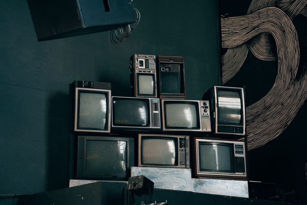 A stack of vintage CRT televisions in a dimly lit modern room with abstract art. — IPTV Offers Family-Friendly Entertainment
