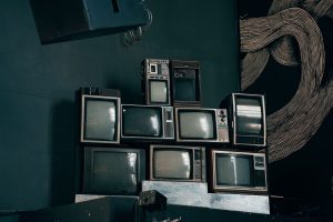 A stack of vintage CRT televisions in a dimly lit modern room with abstract art. — IPTV Offers Family-Friendly Entertainment